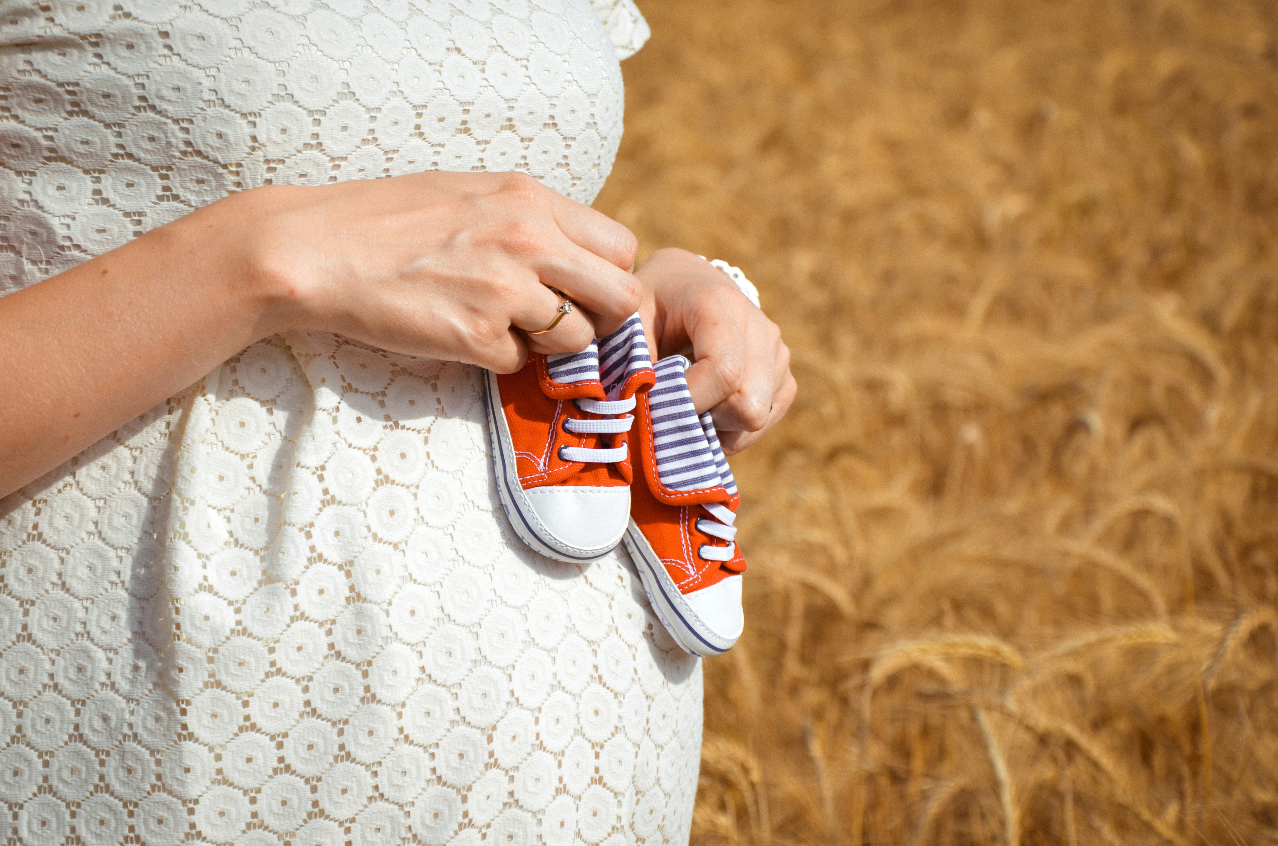 Pregnant woman holding baby shoes on top of pregnant stomach